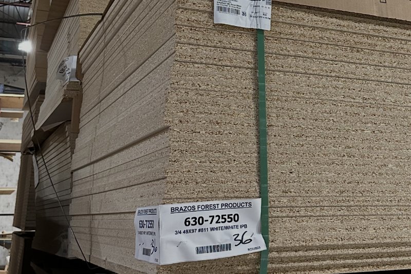 Stacked panel stock tagged with a Brazos Forest Products inventory label in the warehouse