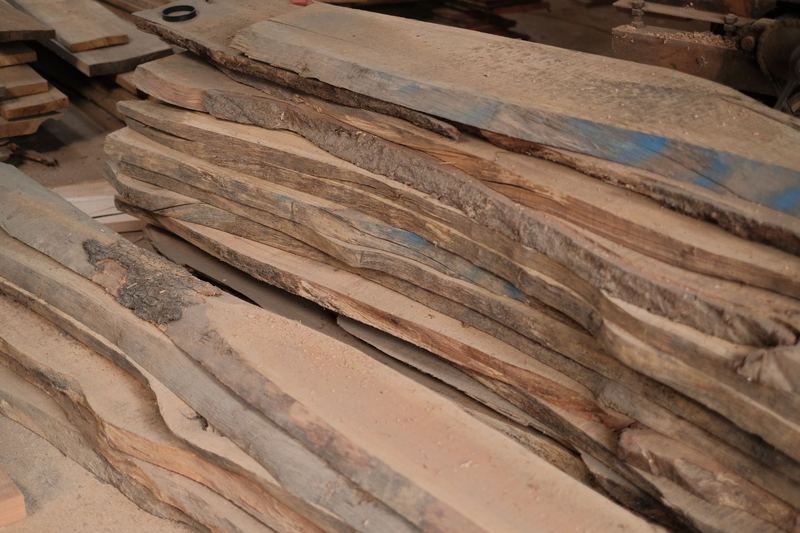 Raw live edge wood slabs stacked in a workshop